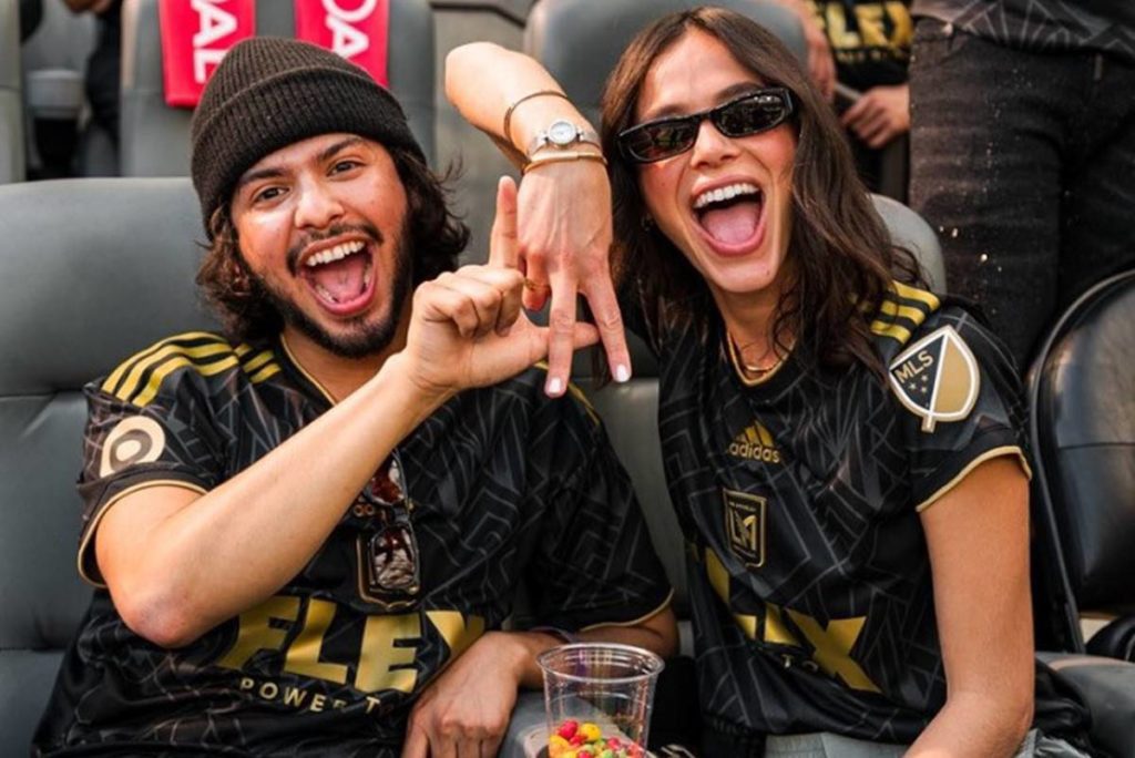 Foto colorida de Bruna Marquezine e Xolo Maridueña assistindo jogo e comemorando - Metrópoles