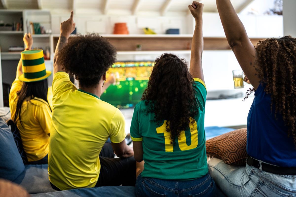 Família acompanhando partida de futebol em frente à televisão