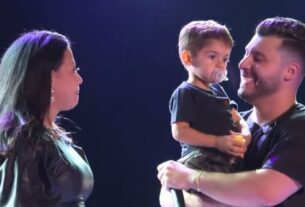 Murilo Huff, ex de Marília Mendonça e pai de seu filho Léo canta com o menino no colo durante show em homenagem à cantora.  Ao seu lado, a mãe de Marília, Dona Ruth, observa sorrindo - Metrópoles