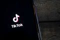 Celular sob mesa mostra aplicativo e logotipo do TikTok - Metrópoles