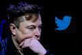 Elon Musk, dono do Twitter, aparece pensativo ao lado de um logo da rede social.  Ele poderá cobrar pelo selo de verificado - Metrópoles