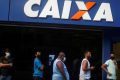 Pessoas em frente a uma agência da Caixa