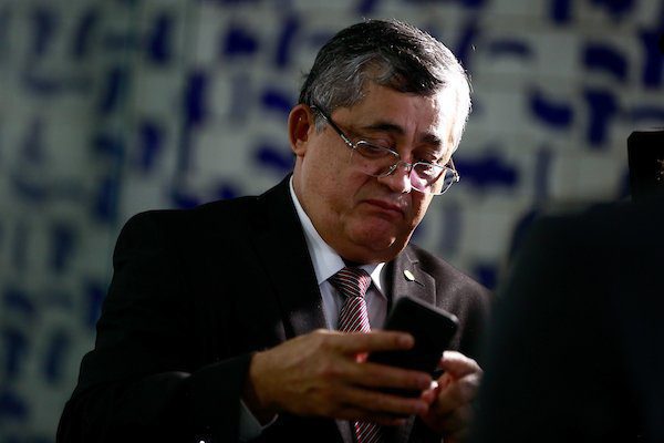 O deputado petista e membro da equipe de transição do governo Lula, José Guimarães. Ele usa óculos, olhando e mexendo em celular com mural da Câmara ao fundo - Metrópoles