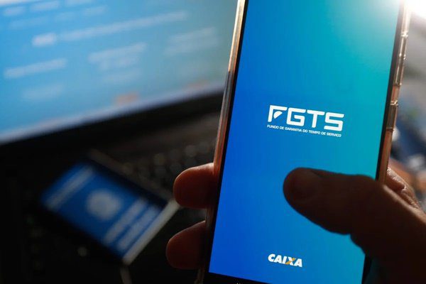 foto mostra uma pessoa segurando um celular com a tela aberta no aplicativo do FGTS